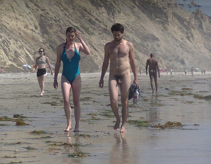 Naked men on the beach among dressed