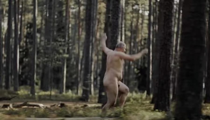 A naked guy runs through the woods